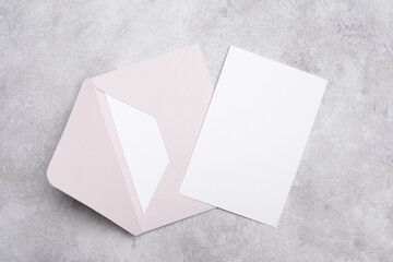 Blank white stationery paper card with light pink envelope on a textured gray background, suitable for invitations, greetings or personal correspondence © nikavera