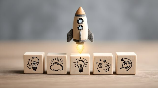 Toy wooden rocket launching off line of wooden blocks printed with lightbulb and creative icons.