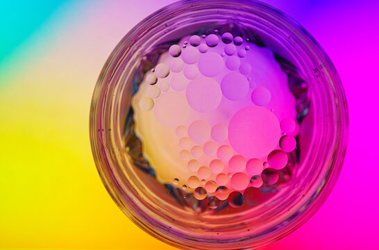 Oil and water droplets in a glass container with a colorful background