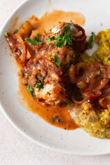 Fototapeta premium Servings of porridge mix with amaranth, millet, and quinoa sit next to baked white hake covered in tomato sauce. This meal is healthy and gluten-free