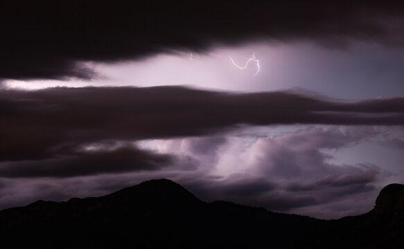 Huachuca Mountains silhouetted at night by distant lightning strikes