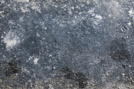 The Asphalt Surface with Weathered Texture and Pebble Granules Close-Up