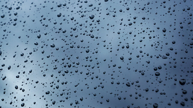 Water droplets on transparent glass. Glistening water drops on the surface of clear, bluish glass.