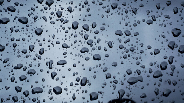 Water droplets on transparent glass. Glistening water drops on the surface of clear, bluish glass.