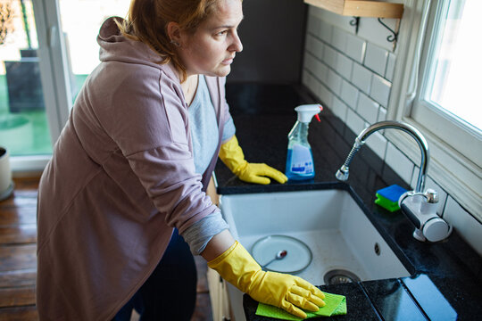 Woman cleaning kitchen sink countertop at home