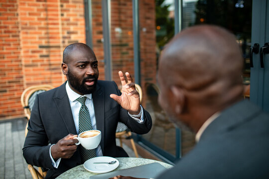 Two businessmen discussing strategy over coffee at outdoor cafe