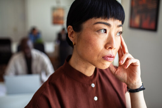 Concerned businesswoman touching temple in office