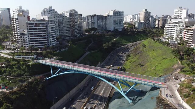 Aerial footage of modern buildings and a pedestrian bridge over a busy highway in miraflores, lima