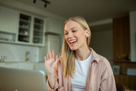 Smiling woman waving on video call at home