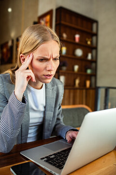 Concerned businesswoman working on laptop in cafe