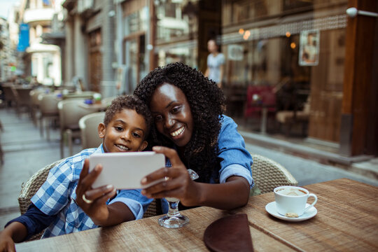 Smiling mother and son taking a selfie at street cafe