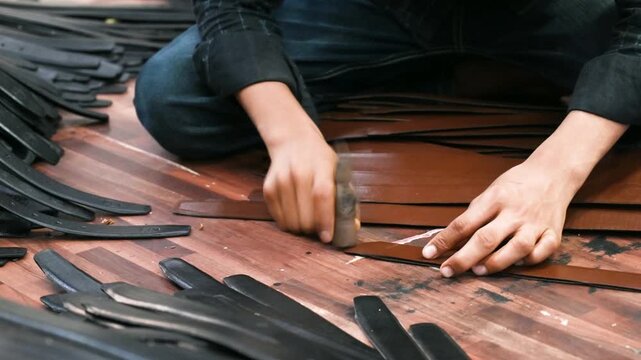 Mumbai, Maharashtra, India - 31 July 2026: View of a leather worker meticulously cutting and preparing leather strips for belt manufacturing in a workshop.