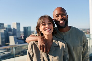 Naklejka premium Smiling couple on a rooftop skyline portrait background with city view for social media and lifestyle use