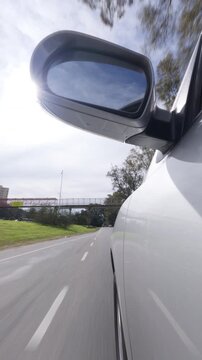 Driving SUV / car through city street / road - side mirror POV daytime. Vertical