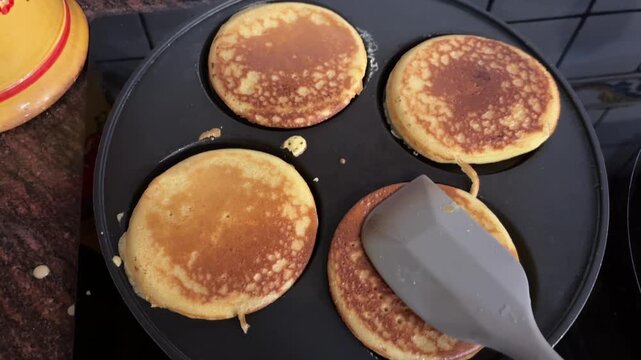 Manos aplanando pancakes con paleta en sart&eacute;n especial