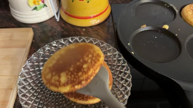Manos colocando pancakes en un plato desde la sart&eacute;n