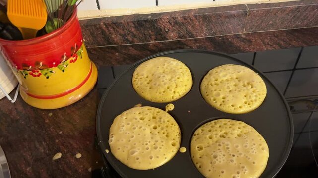 Mano quitando tapa de sart&eacute;n con cuatro pancakes