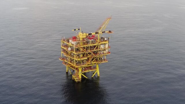 Aerial view of multi-level offshore production platform with crane and safety railings in calm sea, with platform, offshore, oilrig, rig detail, showing structure, industrial, marine, ocean context