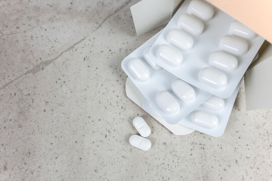 White pills and cardboard box on the stone background with place for text.