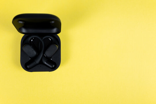 Black wireless headphones for mobile phone. New black earphones for smartphoneon the stone table. New technologies.