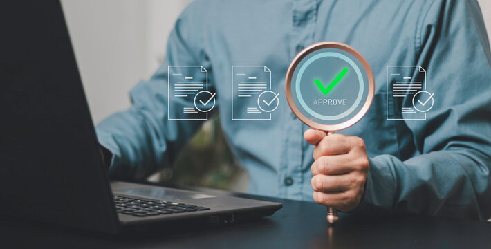 Compliance, verification, approved, regulatory audit, legal review, and governance. Professional reviewing digital documents with a magnifying glass and mark right icon beside laptop.