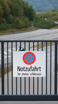 Geschlossenes Tor einer Notzufahrt zur Autobahn mit Hinweisschild in der Schweiz