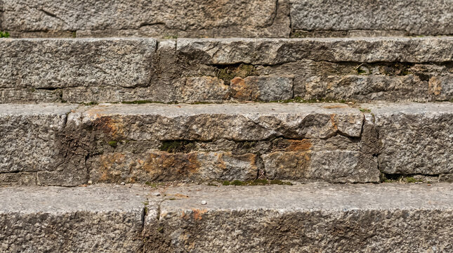 Stone steps texture showing ancient gray masonry architecture with rough granite details and moss growing