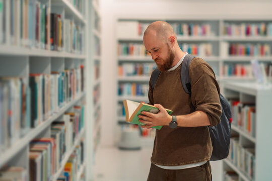 Man reading an open book standing in a library