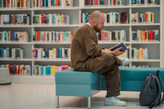 Man reading on a bench with a backpack on the floor