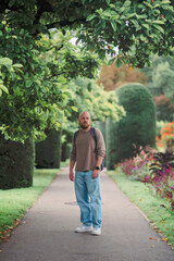 Fototapeta premium Man walking along a green alley in a city park