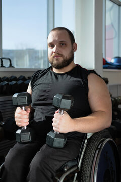 Disabled man wheelchair holding dumbbells gym