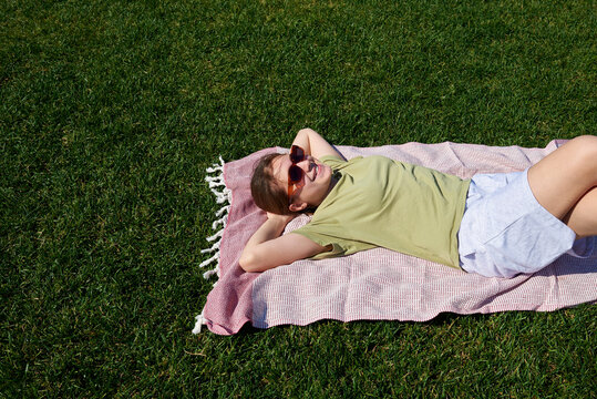 Teenage girl lying on a lawn during sunny day