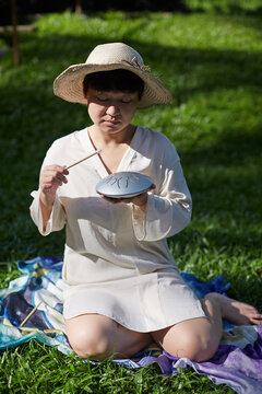 Chinese woman playing a hollow drum on the grass