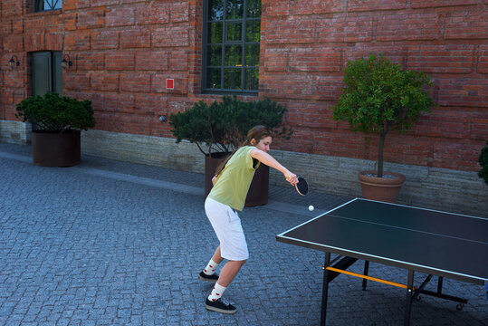Teenager plays table tennis outside