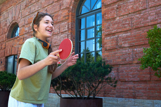 Teenager plays table tennis outside a brick building