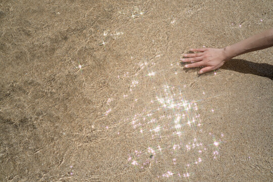 Hand Touching Clear Seawater Over Sandy Beach