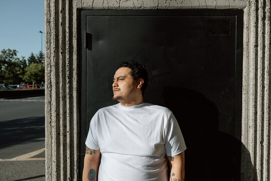 Candid portrait of man in white t-shirt leaning in sunlight