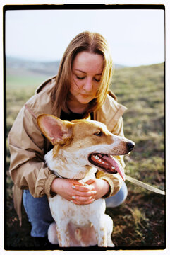 Film outdoor photo of a young woman gently hugging her dog with care