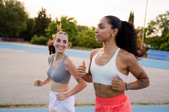 Diverse women running outdoors on track together