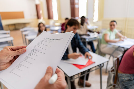 Instructor checking general knowledge exam papers in classroom