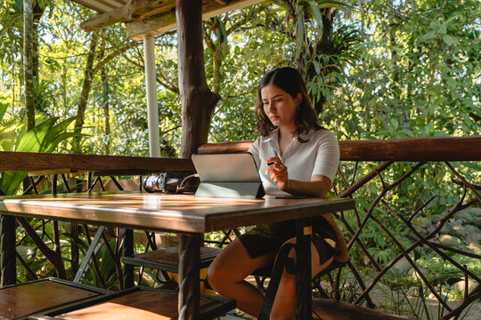 Professional working remotely with tablet in lush jungle environment