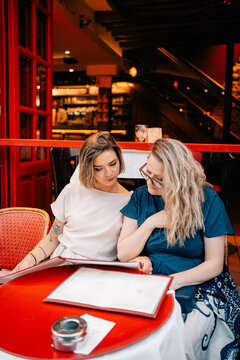 Two Friends Read a Menu Together in a Cafe in the Evening
