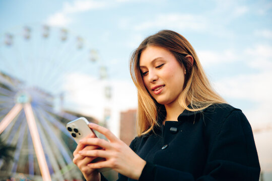 Young woman holding smartphone at fairgrounds