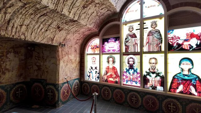 Coober Pedy, South Australia - 15 May 2025: View of the underground Serbian Orthodox Church featuring a cross-shaped baptismal font and religious iconography carved into stone walls.