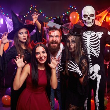 Group of friends in scary halloween costumes posing at a party