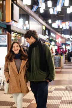 Happy young couple walking city street at night