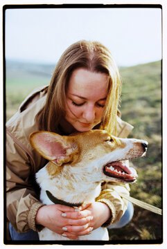 Film outdoor close up portrait of a woman gently hugging her dog 