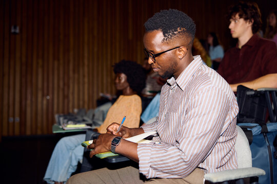 Individual jotting down notes at a conference event in a hall
