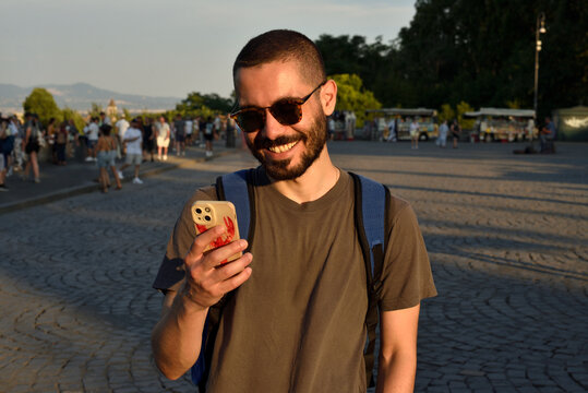 Happy Young Traveler Reading a Message While Exploring a European City