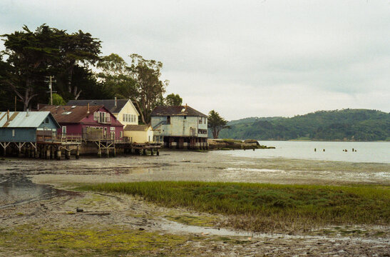 Colorful stilt houses on a tidal mudflat under an overcast sky